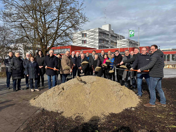 Spatenstich durch die Personen: Rainer Sonnleitner, Schulleiter Mittelschule Dorfen; Robert Leiter, Schulamtsdirektor; Erster Bürgermeister Heinz Grundner, Silvia Makas, Sachgebietsleitung KiTa BRK-Kreisverband Erding; Sonja Blaha, Schulleiterin Grundschule Dorfen Nord; Landrat Martin Bayerstorfer, Sevket Dalyanoglu, Architekt Projektbüro 678; August Kapser, Leiter Hochbauamt Stadt Dorfen; Thomas Gößlinger, Palitza Hoch- und Tiefbau GmbH; Markus Fischer, SÄBAU Holzbau GmbH. Im Hintergrund weitere geladene Gäste und die Grund- und Mittelschule.