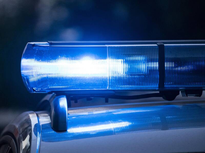 Ein eingeschaltetes blaues Blaulicht auf einem Polizeifahrzeug leuchtet in der Dämmerung.