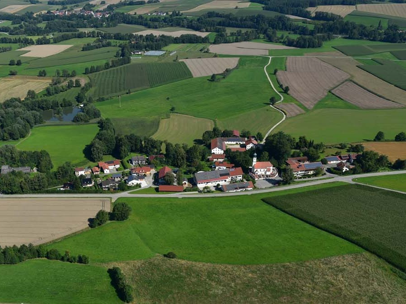 Eine Luftaufnahme zeigt Watzling bei Dorfen in einer ländlichen Gegend mit vielen Feldern und Wiesen.