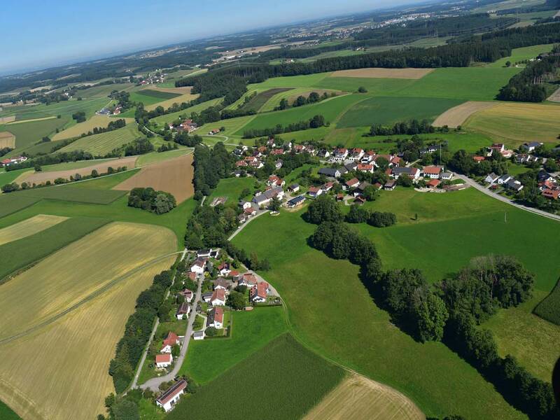 Das Bild zeigt eine weitläufige Landschaft aus der Vogelperspektive mit grünen Feldern und Wiesen sowie Eibach mit seinen Häusern in der Mitte.