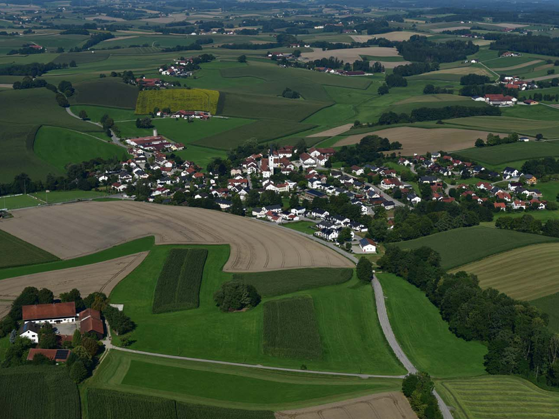 Das Bild zeigt eine ländliche Landschaft mit der Ortschaft Grüntegernbach, umgeben von grünen Feldern und Wäldern.