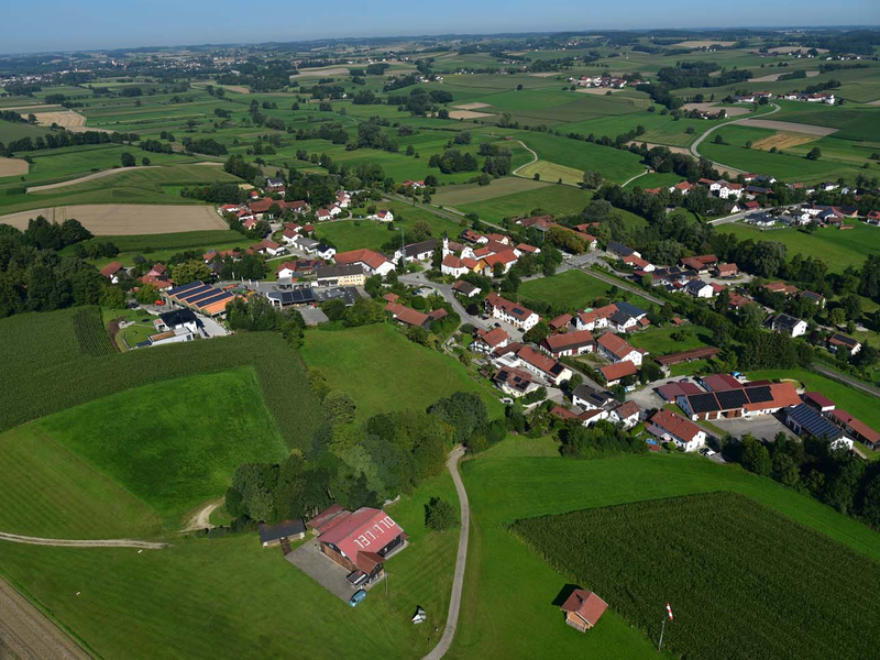 Das Bild zeigt eine Luftaufnahme von Wasentegernbach, einer kleinen Ortschaft, umgeben von grünen Feldern und Bäumen.