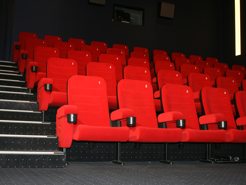Ein leeres Kino mit mehreren Reihen roter Sitze, die nummeriert sind.