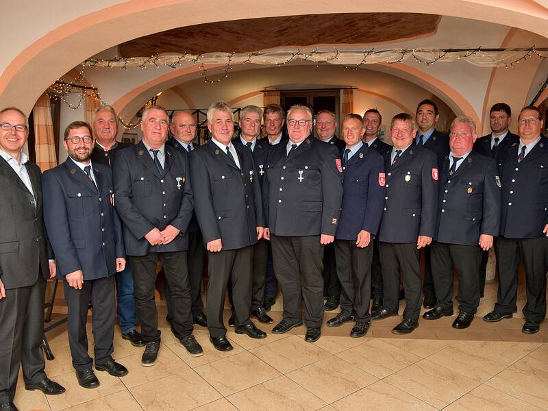 Eine Gruppe von Männern in Uniformen steht in einem festlich dekorierten Raum zusammen.